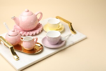 Tray with beautiful ceramic tea set for children on beige background, closeup. Space for text
