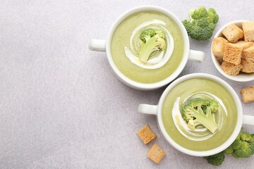 Tasty broccoli cream soup served with croutons on light grey table, flat lay. Space for text
