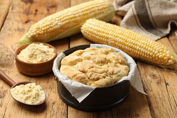 Freshly baked cornbread, flour and cobs on wooden table, closeup