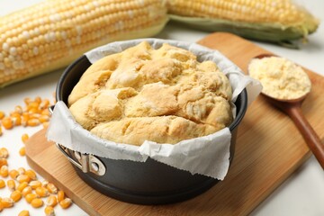 Freshly baked cornbread, seeds, flour and cobs on white table, closeup