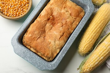 Freshly baked cornbread, seeds and cobs on white marble table, flat lay