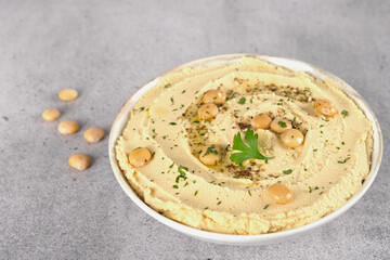 Creamy lupini hummus with olive oil, herbs on gray background. Vegan, healthy food concept.