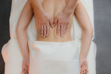 An individual lies comfortably while receiving a back massage from a professional therapist in a tranquil and serene setting that promotes relaxation