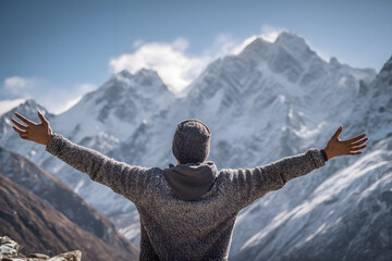 Man with arms wide open facing snowy mountains. Lifestyle image symbolizing freedom and adventure