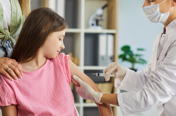 Child receives vaccination injection from doctor. A nurse uses a syringe to vaccinate the patient arm during medical clinic visit, emphasizing careful healthcare. Kids' vaccines keep children safe.