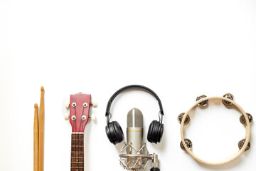 Recording music in a studio. Musical instruments for band - small guitar, drumsticks and tambourine - with studio microphone