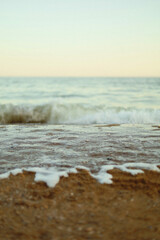 White sea foam covering sandy beach