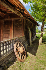 Detail of an old wooden Georgian house with a vintage cart wheel leaning against the wall. Rich textures and rural nostalgia