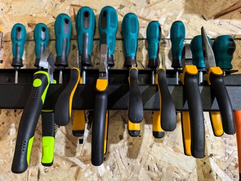 Assorted hand tools on wall rack, vibrant colors, organized workspace
