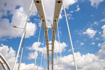 arched bridge against blue sky with clouds. arch's arrow. arch is connected to the roadway by...