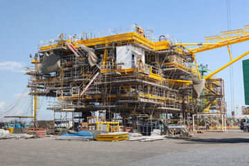Offshore oil rig under construction with metal framework and mechanical and electrical systems. Represents engineering technology, petroleum industry, oil gas business, global energy investment.