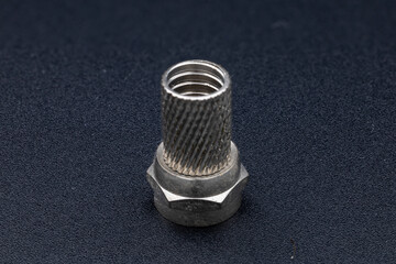 Detailed close-up of a textured metal coaxial F-connector, on a dark background