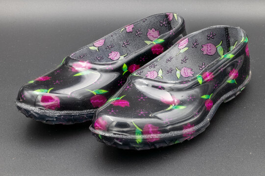 Pair of colorful, patterned plastic clogs on a dark background, footwear concept