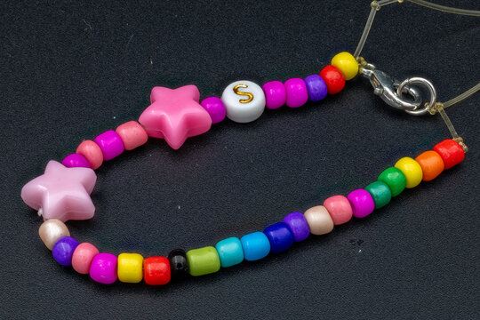 Colorful handmade bracelet with beads and stars on a dark background
