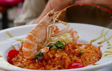 Girl sitting at the table eating sea food shrimps risotto mediteranen food background