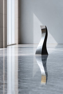Elegant abstract sculpture reflected on a glossy marble floor, bathed in soft light. A symbol of modern art, design, and minimalist aesthetics.