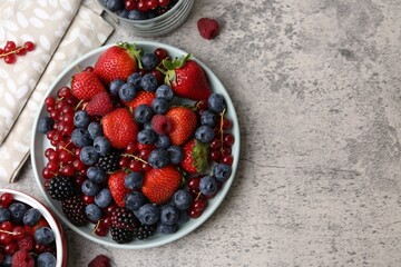 Different ripe berries on light grey textured table, flat lay. Space for text