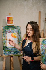 Teacher learn children to draw pictures in an art lesson. Painting in workshop. Artist explains how to mix and combine colors. Woman drawing brush on easel. Education, learning concept. Closeup.