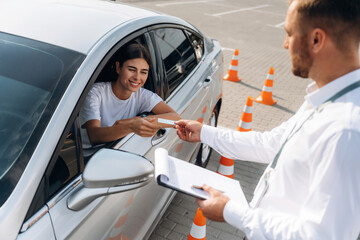 Congratulations giving the license, passed. Woman is trying to pass exam in the driving school