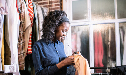 Woman Shopping For Clothes In A Boutique, Selecting Blue Shirt From Racks Displayed On Hangers