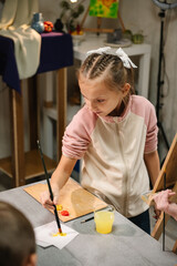 Girl mixed and combined colors. Education and learning concept. School kid drawing with brush on easel. Girl enjoys painting in a workshop. Art lesson. Children drew a picture in art class. Closeup.