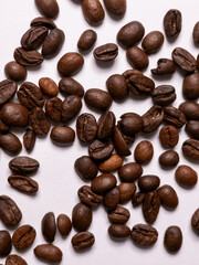 Roasted coffee beans scattered on white background
