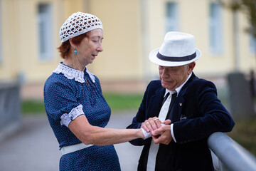 Elderly pair shares a gentle moment near the building in the late after