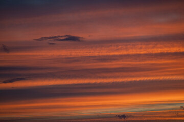 Colors blend beautifully in the sky as the sun rises, casting warm tones of orange and yellow through fluffy clouds.
