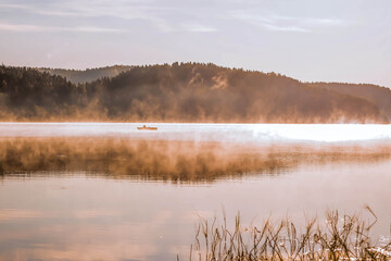 Beautiful morning foggy landscape. Lake Ladoga with a fishing boat in the fog. Beautiful natural background. Republic of Karelia, Russia.