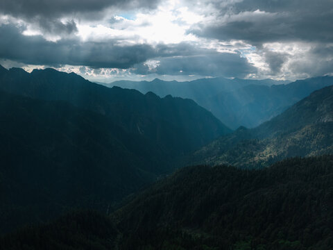 Aerial view of the dramatic, cloud-draped mountains with light filtering through, creating a serene yet powerful landscape, Sosan, Himachal Pradesh, India.