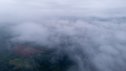 Aerial of Village in rain cloud cover tropical green mountain. Rainy season. Misty cover green forest. beautiful green village