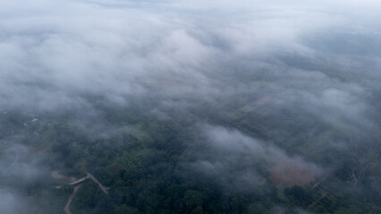 Aerial of Village in rain cloud cover tropical green mountain. Rainy season. Misty cover green forest. beautiful green village