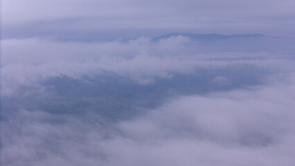 Aerial of Village in rain cloud cover tropical green mountain. Rainy season. Misty cover green forest. beautiful green village