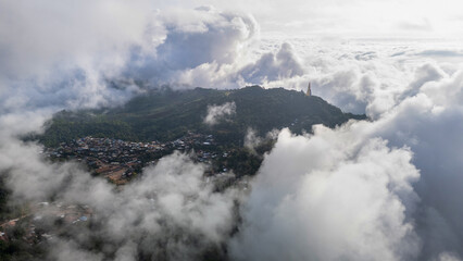 Aerial of Village in rain cloud cover tropical green mountain. Rainy season. Misty cover green forest. beautiful green village
