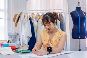 A young female dressmaker working on cloth pattern,creating new fashion design clothes in atelier