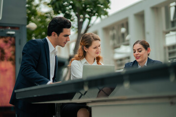 Fototapeta premium Three professionals discussing project outdoors, teamwork and collaboration highlighted with laptop, symbolizing flexible work culture at rooftop hotel.
