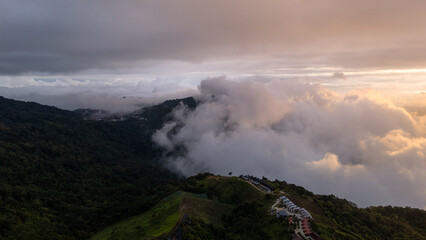 Aerial of Village in rain cloud cover tropical green mountain. Rainy season. Misty cover green forest. beautiful green village