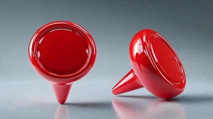 Two shiny red egg shaped objects with pointed bases on a neutral background
