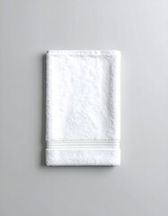 Folded white bath towel against a plain gray background