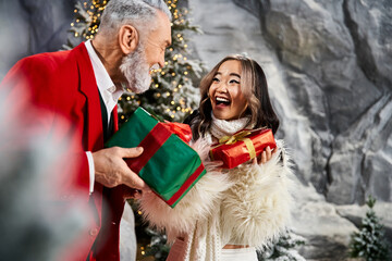 Elderly man in red suit and young woman in white joyfully celebrate Christmas