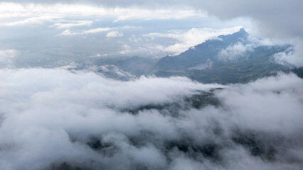 Aerial of Village in rain cloud cover tropical green mountain. Rainy season. Misty cover green forest. beautiful green village