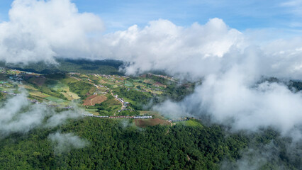 Aerial of Village in rain cloud cover tropical green mountain. Rainy season. Misty cover green forest. beautiful green village