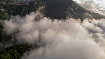 Aerial of Village in rain cloud cover tropical green mountain. Rainy season. Misty cover green forest. beautiful green village