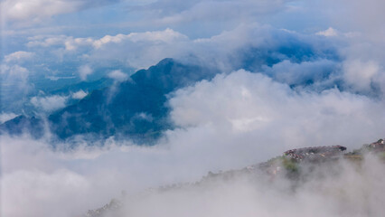 Aerial of Village in rain cloud cover tropical green mountain. Rainy season. Misty cover green forest. beautiful green village