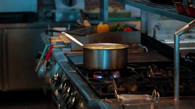 Essential process of cooking in a restaurant, showing a stainless steel pot boiling over a hot gas flame with steam rising, a fundamental step in food preparation