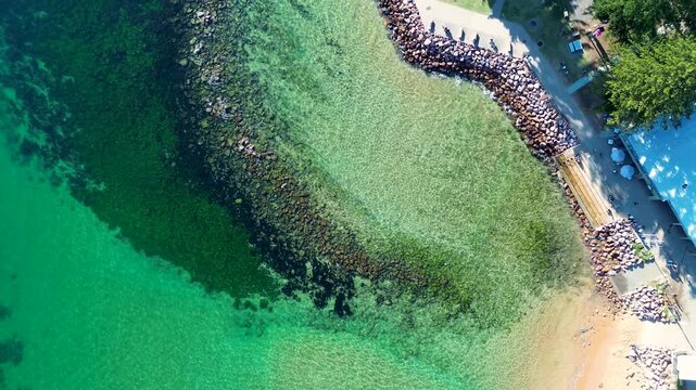 Drone aerial landscape of calm clear ocean water at Avoca Beach rocky reef pool with local caf&eacute; and public pathway along the scenic waterfront on the Central Coast Australia travel nature holidays