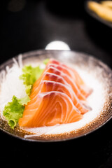 Salmon sashimi on black ceramic plate. Japanese traditional food or with low calories and high nutrition and healthy diet dish.