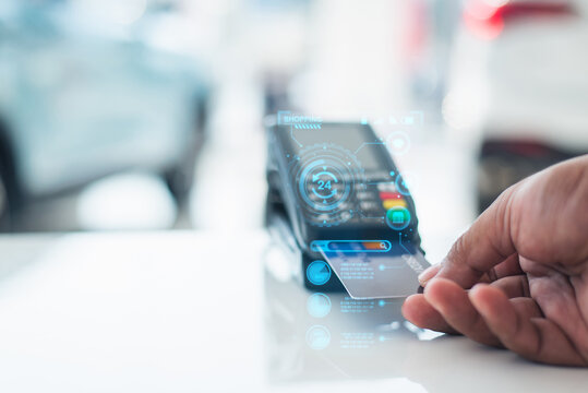 Close-up of a hand using a credit card on a payment terminal with holographic interface, symbolizing digital banking, fintech, and cashless transactions.