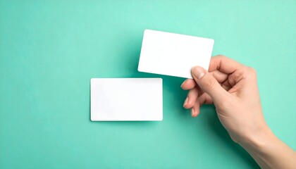 Two blank white cards held by a hand against a mint green background