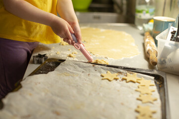 A young child enthusiastically rolls out some delicious cookie dough and skillfully cuts out star shapes to prepare for baking